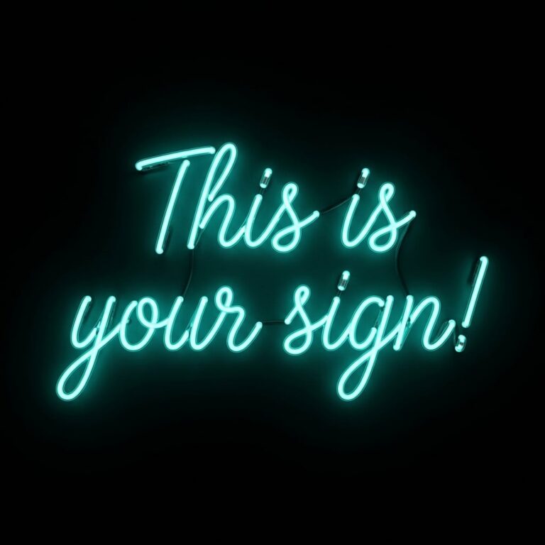 "This is your sign" written in teal blue neon sign lettering